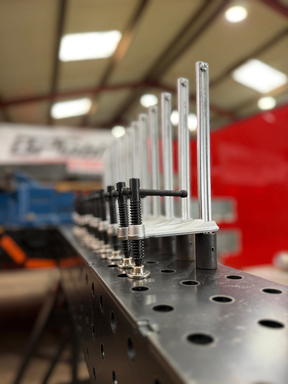 Row of BPT D16 table clamps standing in the 16mm fixture holes along a BPT welding trestle