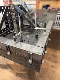 Close-up of BPT slotted end stops bolted through the table's side holes, standing proud of the top as a work stop